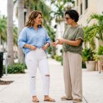 Woman in Miami using a front tuck hack with an oversized linen shirt and denim shorts near the beach