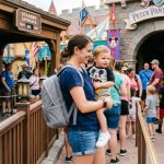 Compact diaper bag unzipped on a Disney hotel bed with organized baby essentials.